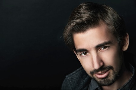 Fashion Shot of a young handsome man in coat on black backgroundの写真素材