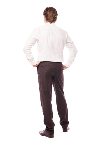 businessman standing back with arms at hips over white backgroundの写真素材
