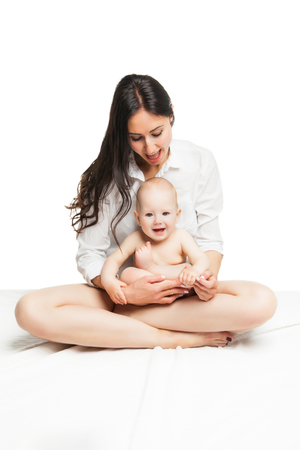 Young mother sitting with cute baby boy huging and posing over white backgroundの写真素材