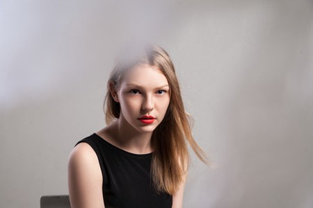 Closeup of Stylish young beautiful girl in elegant black dress with full red lipsの写真素材