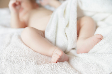 newborn tiny baby lying on the bed with blanket. Focus on feet,の写真素材