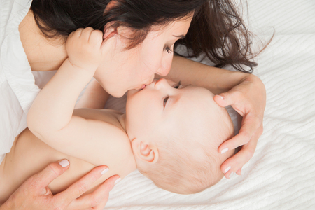 Happy Mother and her Newborn Baby kissing and hugging over whiteの写真素材