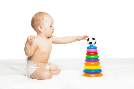 Portrait of cute baby boy sitting and playing with colorful toy over white backgroundの写真素材