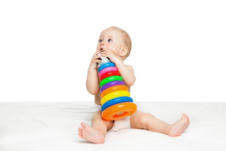 Portrait of cute baby boy sitting and playing with colorful toy over white backgroundの写真素材