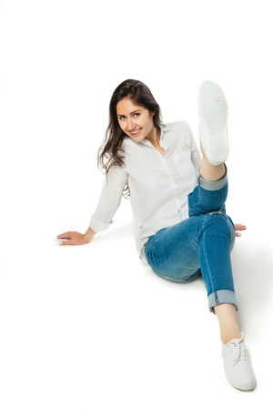 sitting young woman in white shirt and jeans isolatedの写真素材