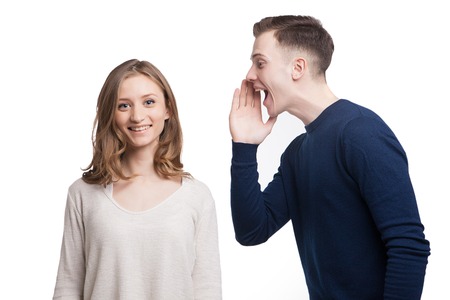 Portrait of smiling woman looking at camera while her boyfriend screaming somethingの写真素材