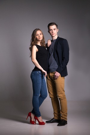 Young couple looking at camera over grey background. Studio shotの写真素材