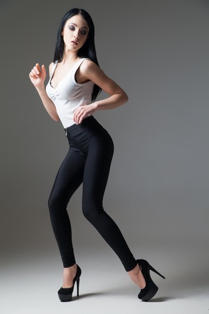 Portrait of beautiful dark-haired model on high heels posing in studioの写真素材