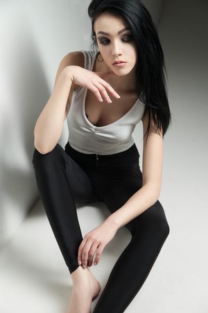 Cloe-up of black-haired model with make-up sitting on floor and looking up.Studio shotの写真素材