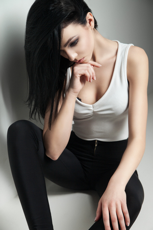 Cloe-up of black-haired model with make-up sitting on floor and looking up.Studio shotの写真素材
