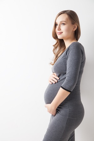 Portrait of happy woman in dress expecting baby.Studio shot.Isolatedの写真素材