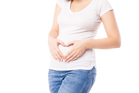 Pregnant woman making heart on belly isolated over whiteの写真素材