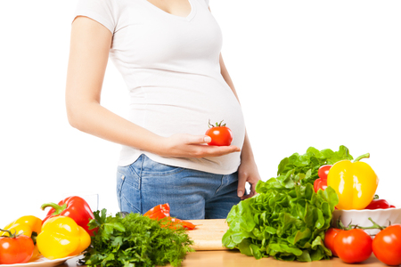 Close-up of pregnant woman holding fresh juicy tomatoの写真素材