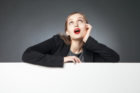 Portrait of surprised woman in jacket with open mouth looking up.Blank spaceの写真素材