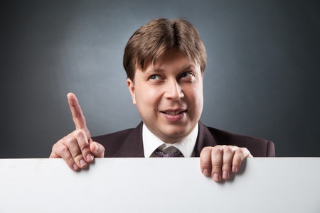 Portrait of adult businessman over blank space with index finger up.Studio shotの写真素材