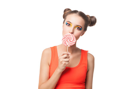 Portrait of beautiful young girl biting candy while looking at camera.Studio shotの写真素材