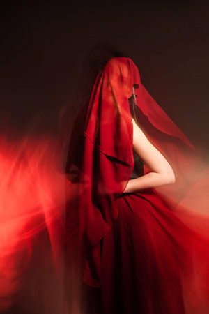 Portrait of unrecognizable woman covered with red cloth.Long exposureの写真素材