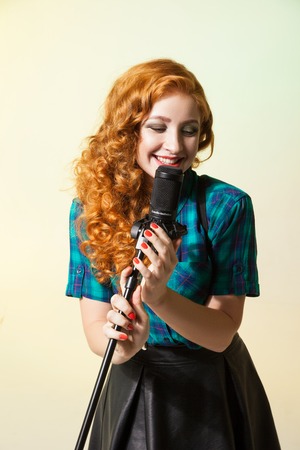 Curly-haired beautiful singer smiling while performing song in mic.Studio shotの写真素材