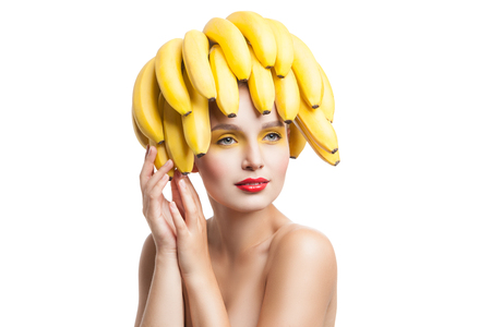 Beautiful fragile model with bunch of bananas on head looking away.Studio shotの写真素材