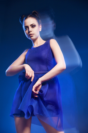 Portrait of beautiful young model posing in blue dress against of blue background.Long exposureの写真素材