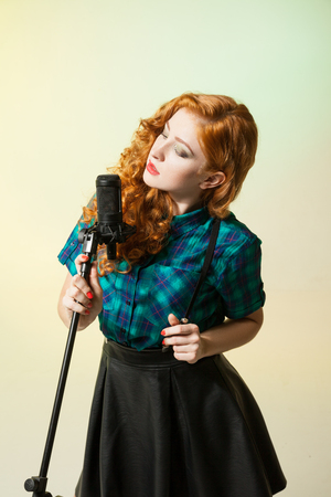 Portrait of attractive singer with red hair singing in mic.Studio shotの写真素材