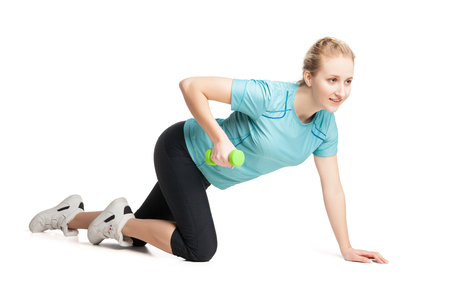 Athletic young woman works out with green dumbbells, isolated on whiteの写真素材