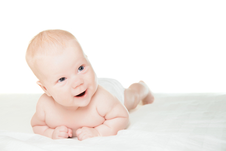 Little boy lying on stomach and smiling over white backgroundの写真素材