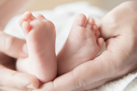 Parent holding his newborn baby's feet close-upの写真素材
