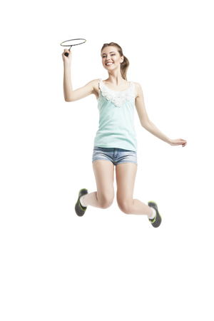 beautiful young girl playing with badminton racket in sneakers over white backgroundの写真素材