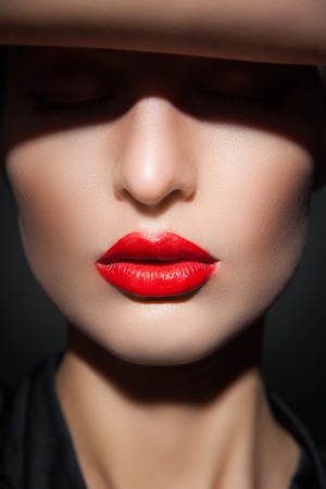 Close-up of young model with eyes closed, red lips and perfect smooth skin in flash lightの写真素材