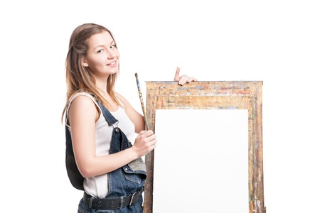 Smiling woman painter with paintbrush standing near  easelの写真素材