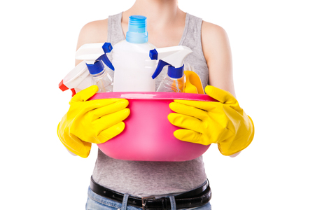 Unknown female holding pink basin with different cleaning substance. Studio photo on white background.の写真素材