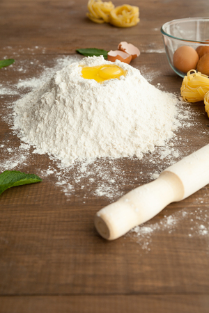 Close up view of cooking dough with fettuccine and eggs nearby with rolling bin in front.の写真素材