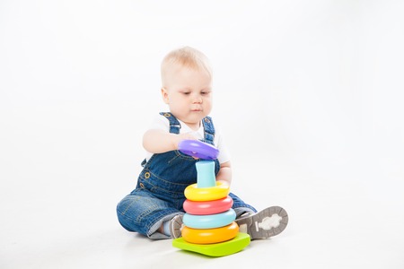 Lovely toddler in denim suit sitting and playing while smiling at camera isolated on white background.の写真素材