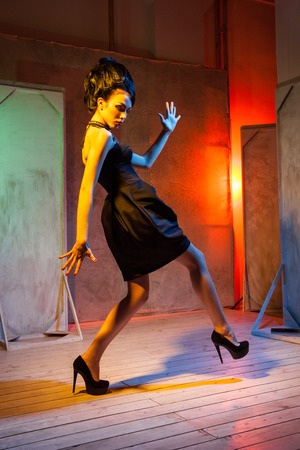 Young high fashion female model posing with hair style and black dress in grunge decorations.の写真素材