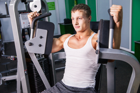 Strong muscular man doing exercise on machineの写真素材