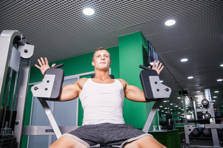 Young sportsman doing chest exercise in gymの写真素材