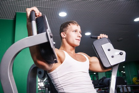 Young sportsman doing chest exercise in gymの写真素材