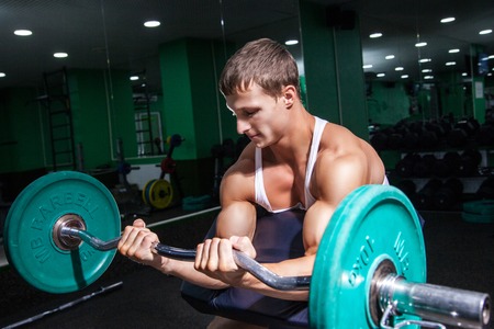 Young sportsman doing biceps exercise in gymの写真素材