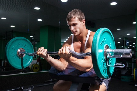 Young sportsman doing biceps exercise in gymの写真素材