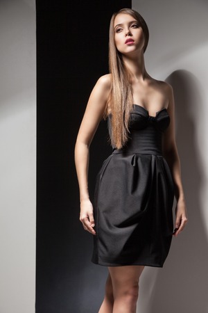 Portrait of beautiful calm long-haired woman in little black dress looking awayの写真素材