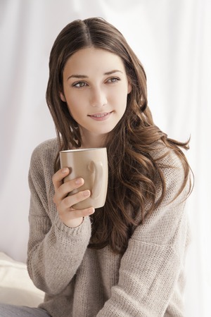 beautiful woman drinking coffee in the morning sitting by the windowの写真素材