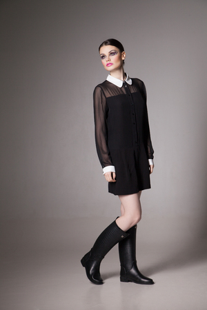 Fashion Image young woman in a stylish transparent  black dress with collar. Posing with one leg bent.の写真素材