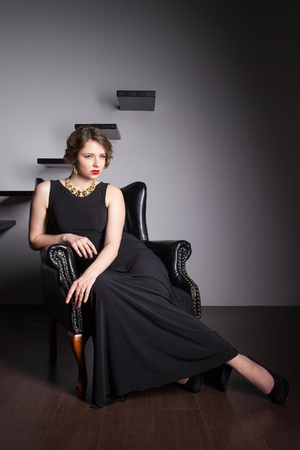 Beautiful elegant woman sitting on an armchairの写真素材