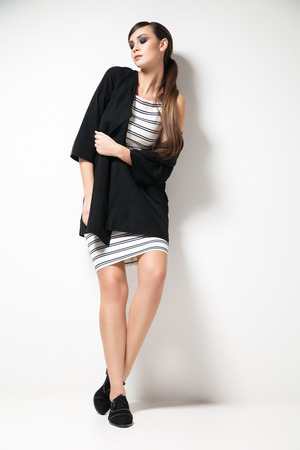 Attractive young woman looking at camera standing in elegant clothes. Vertical studio shot.の写真素材