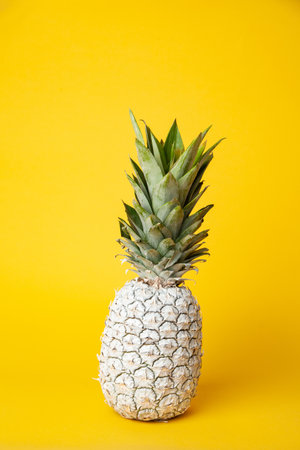 White pineapple on table in studio on yellow backgroundの写真素材