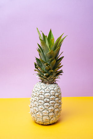 White pineapple on table in studio on violet and yellow backgroundの写真素材
