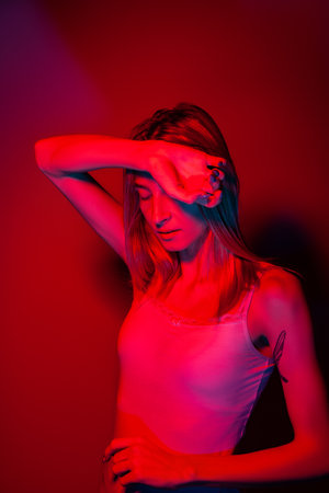 Anonymous woman covering face with hand in red neon lightの写真素材