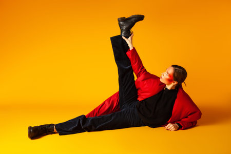 Stylish female model stretching on yellow background