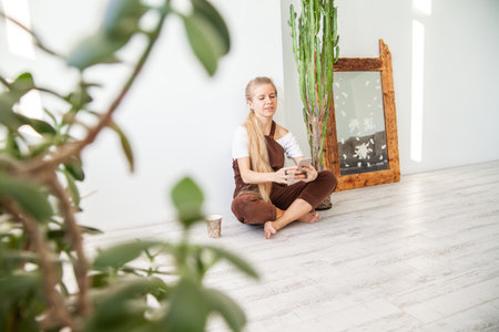 Cheerful young woman with mug using smartphoneの写真素材